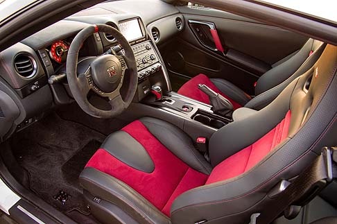Nissan - Il volante rivestito in Alcantara, presenta tre razze, un contrassegno centrale di colore rosso e giunzioni rosse. 