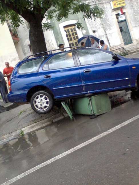 Nubifragio Sud Barese - Vettura station wagon danneggiata dalla forte pioggia, sopra al bidone della raccolta del vetro ad Acquaviva delle Fonti del 14 Giugno 2014